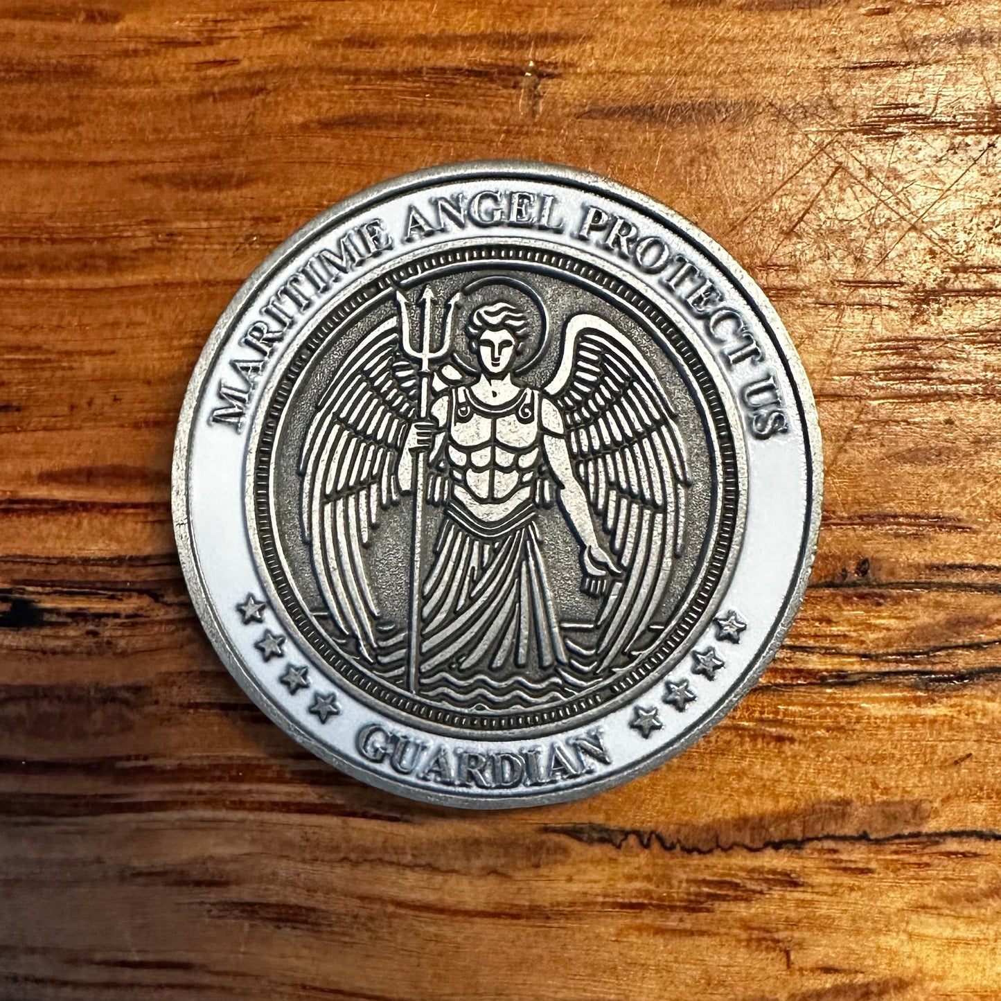 Silver coin with angelic design on a wooden surface